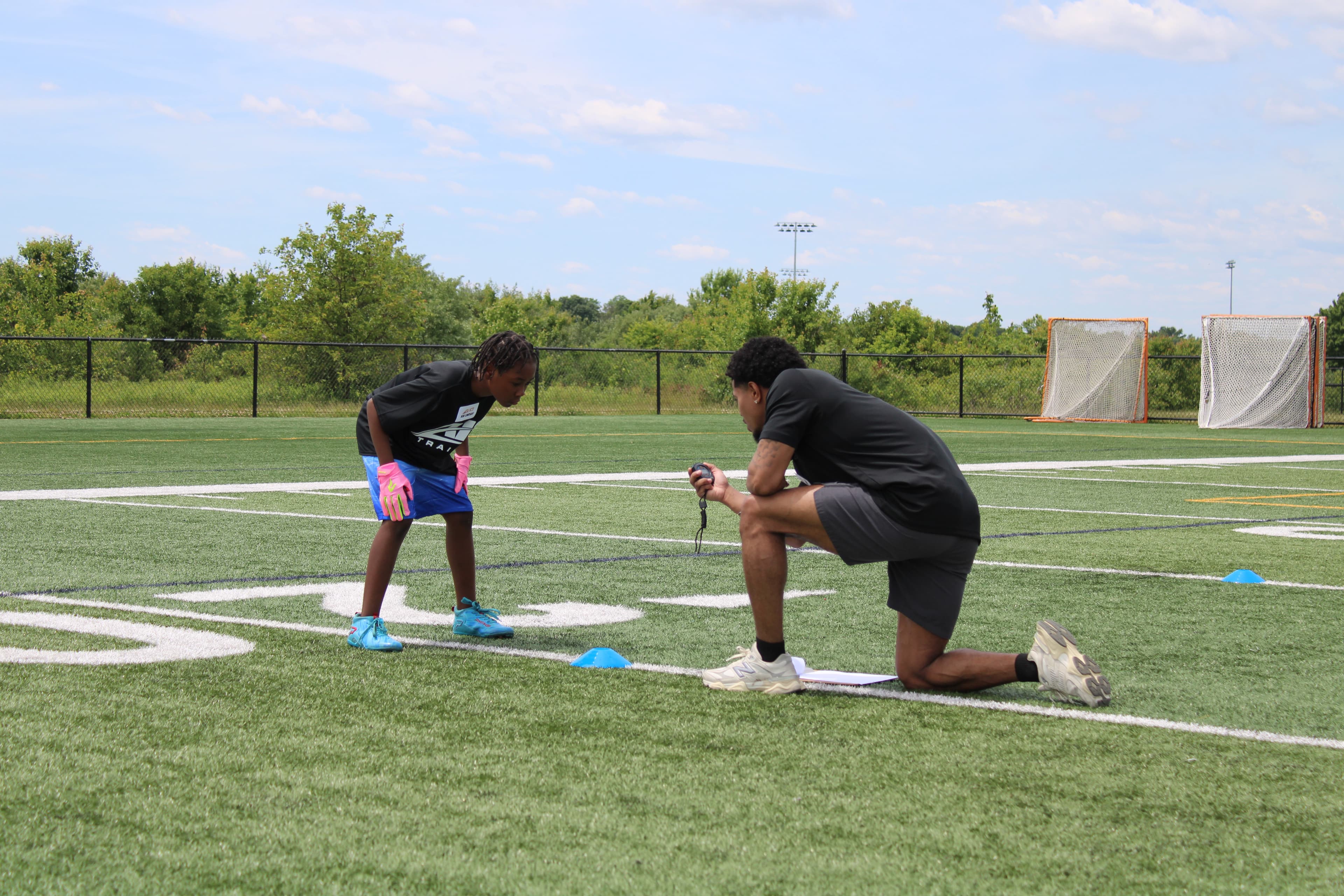Youth football athletes running cone drills on an outdoor field